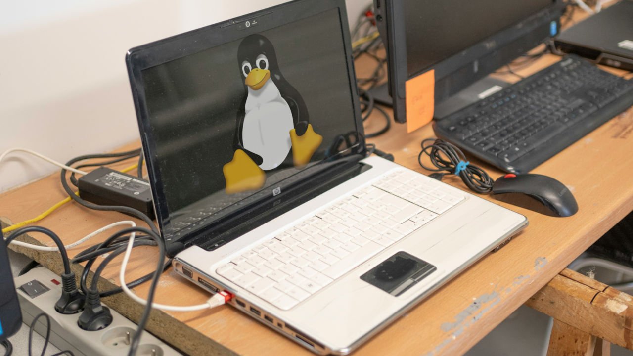 A photograph of an old laptop sitting on a table with cables connected to it.