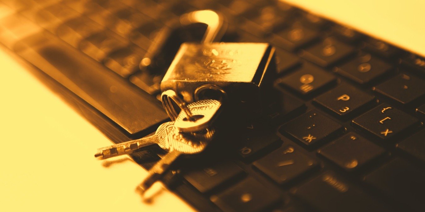 A photograph of a laptop keyboard with an open lock on top of it.