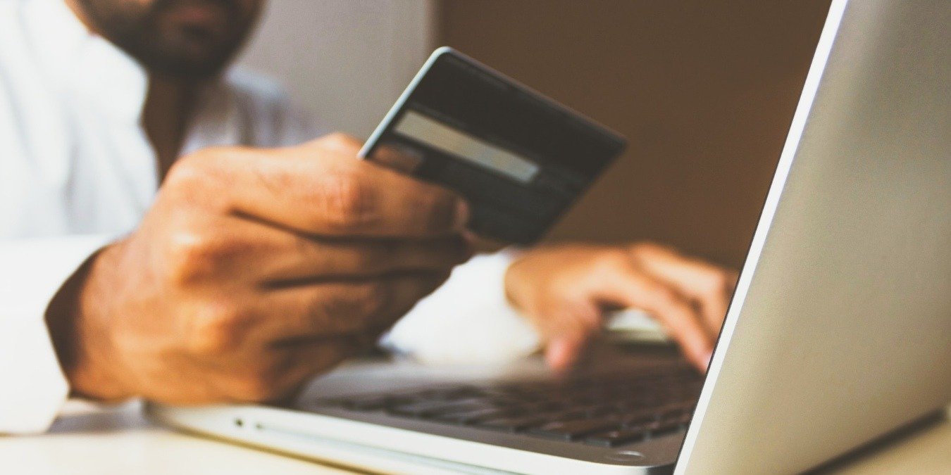 Person using a laptop and holding a credit card
