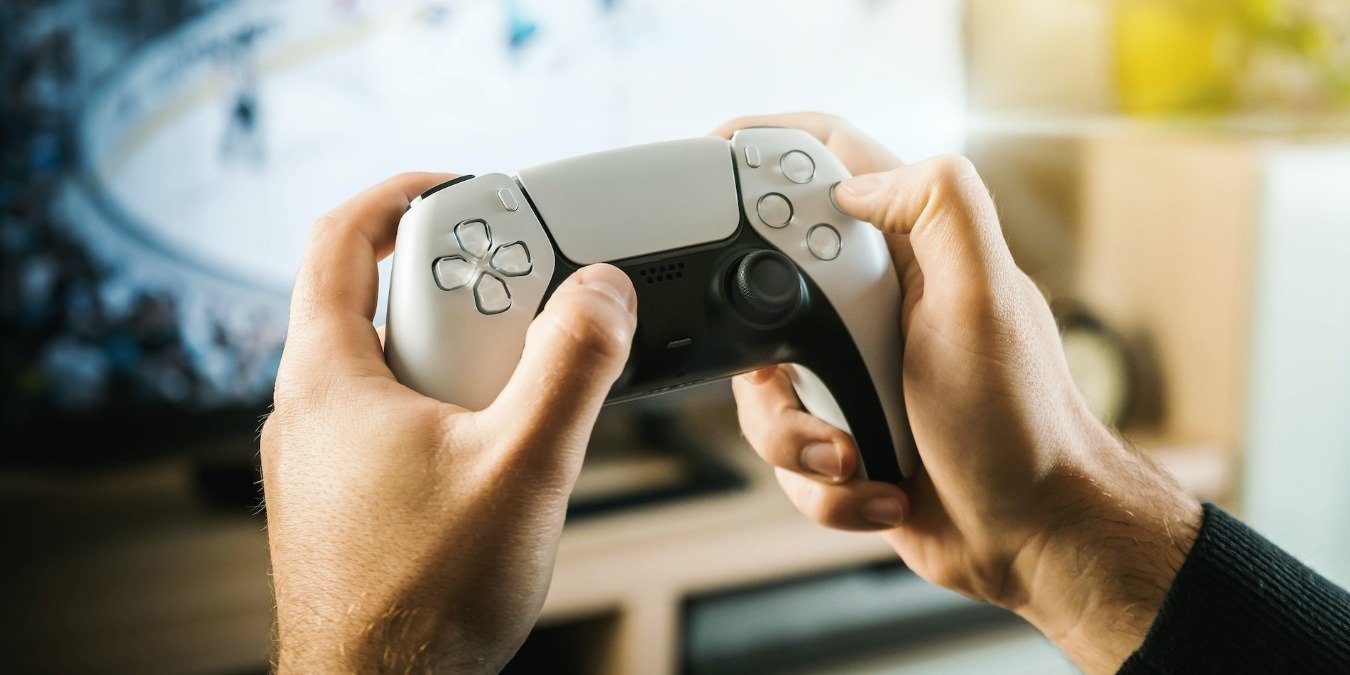 Person holing PlayStation 5 white DualSense controller