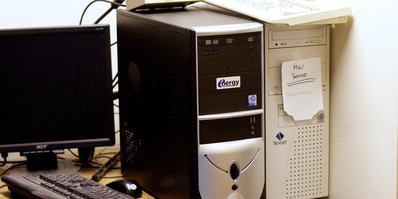Old PCs on a desk alongside a monitor, keyboard, and mouse